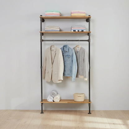 Nino mit Kleidung an der Stange und auf den Regalen versehen an grauer Wand